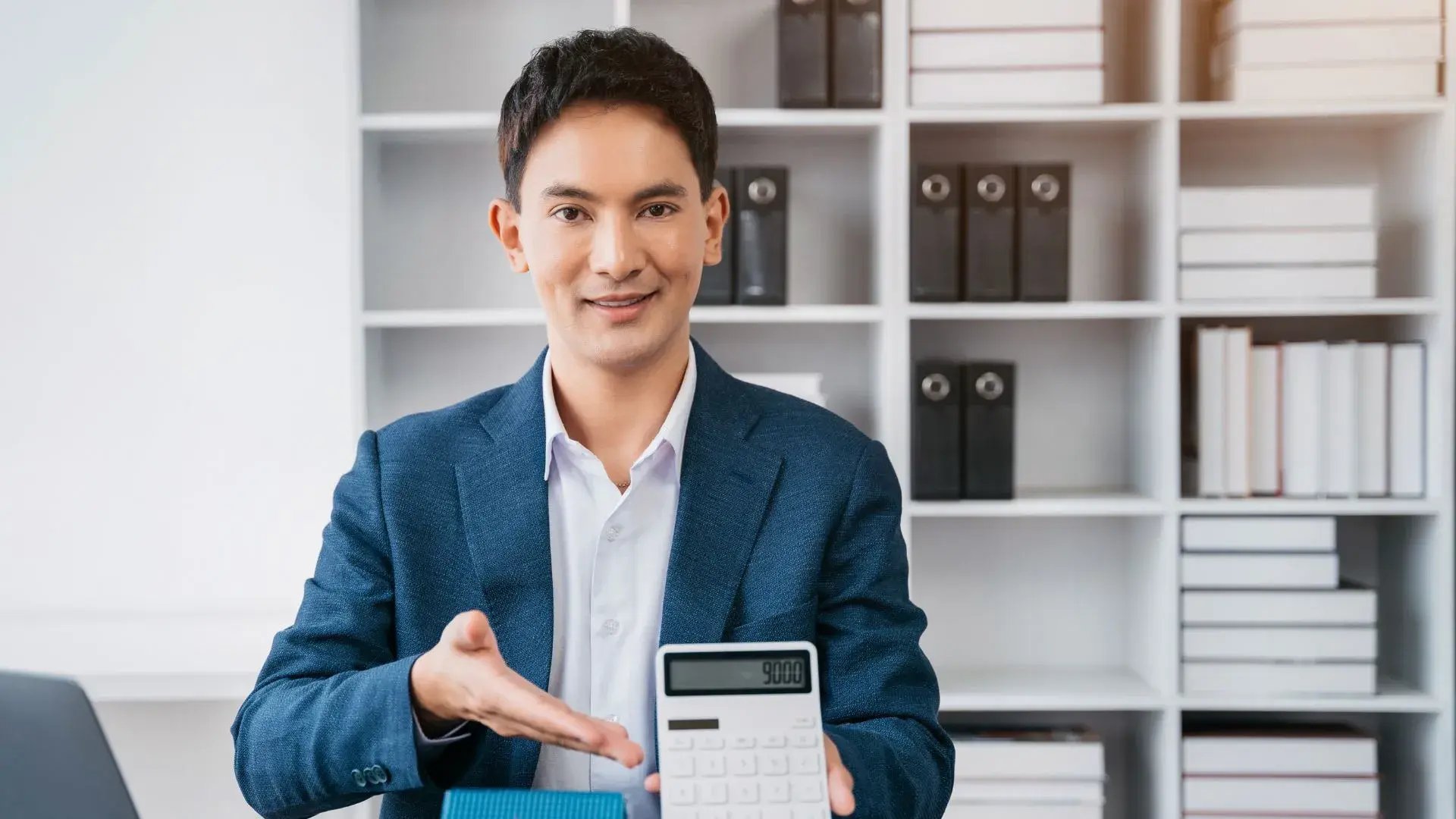 A corporate employee showing cost-cutting figures from a calculator