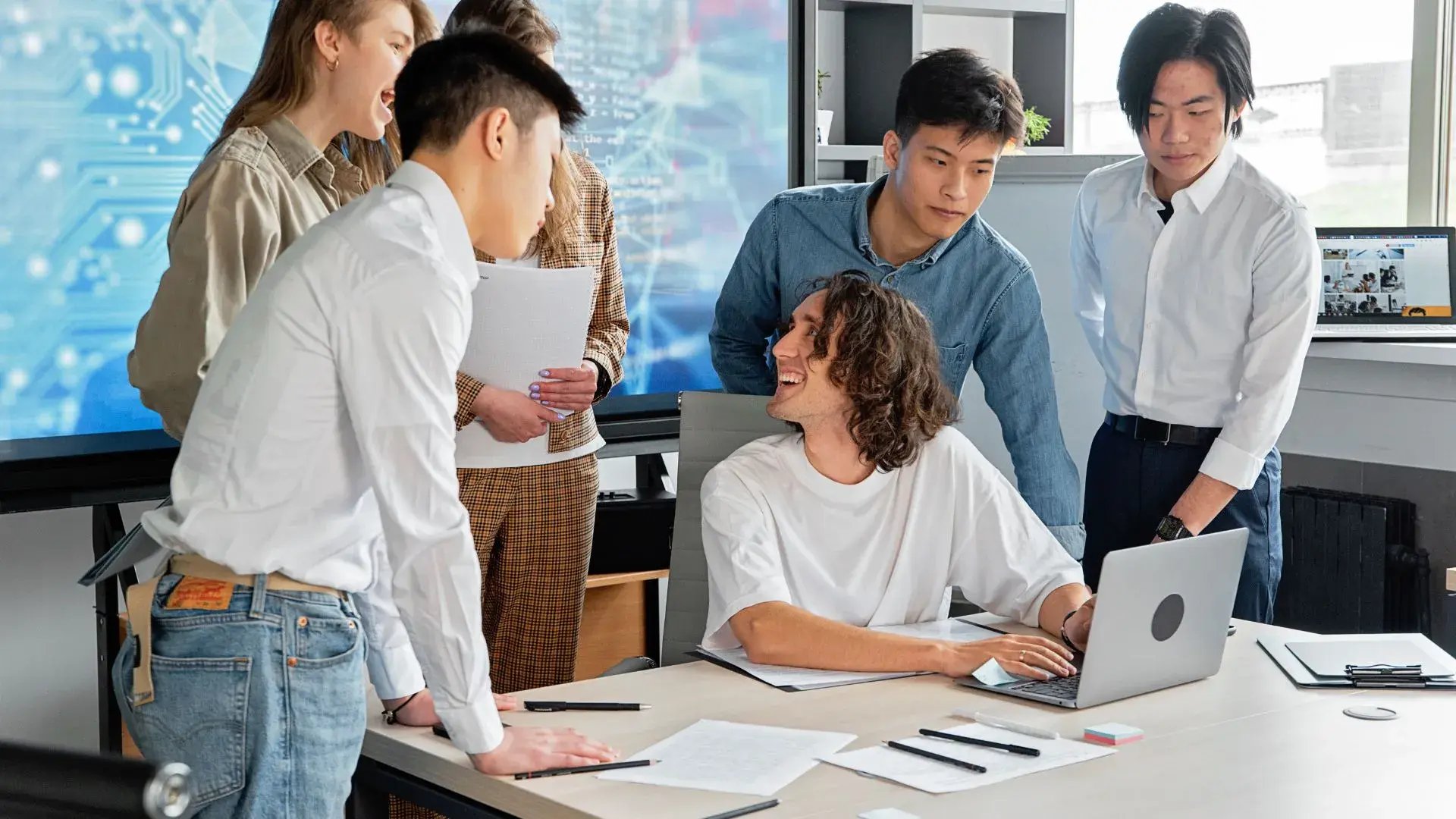 A group of employees having a discussion, presumably about cyber security, while a laptop is open 