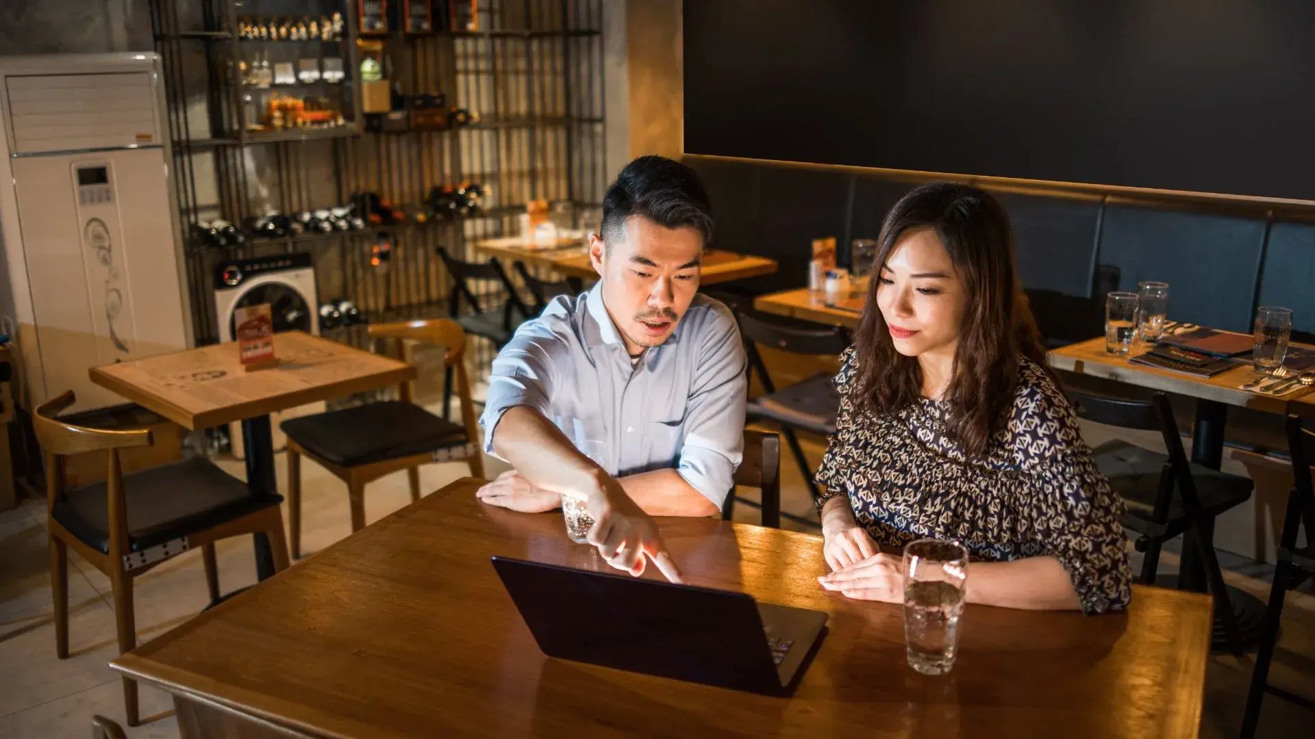 A male and a female business owner are having a discussion  while using their laptop