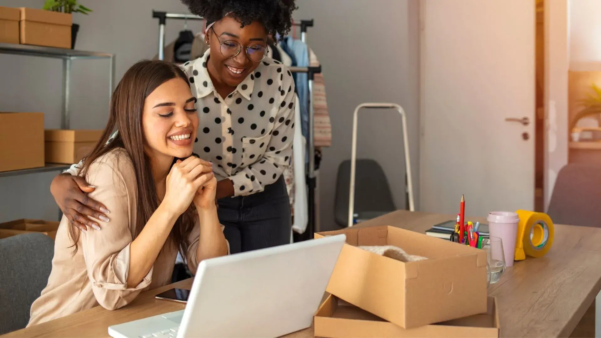 Two women entrepreneurs looking at a laptop screen, likely considering cybersecurity options for their small business