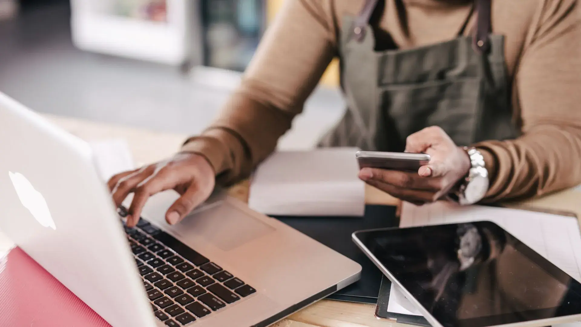 A small business owner using a laptop and his phone